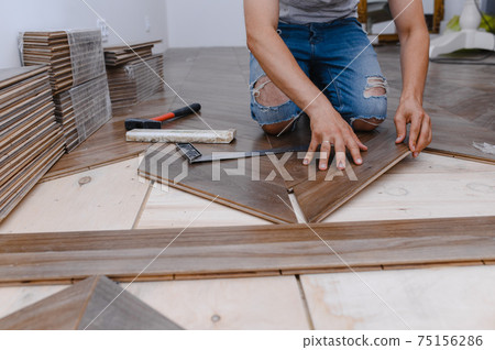 Man laying parquet flooring - closeup on male hands. worker joining parquet floor 75156286
