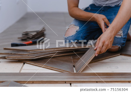 Man laying parquet flooring - closeup on male hands. worker joining parquet floor 75156304