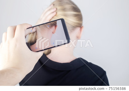 The woman shows his neck with a chip implanted which is read or scanned by a special device. Concept of chipping and implantation of electronic technologies. Cybernetics and the nanofuture. Cyberpunk 75156386