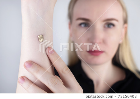 The woman shows his hand with a chip implanted. The concept of chipping and implantation of electronic technologies into the human body. Cybernetics and the nanofuture. Cyberpunk The woman shows his hand with a chip implanted. The concept of chipping and implantation of electronic technologies into the human body. Cybernetics and the nanofuture. Cyberpunk 75156408