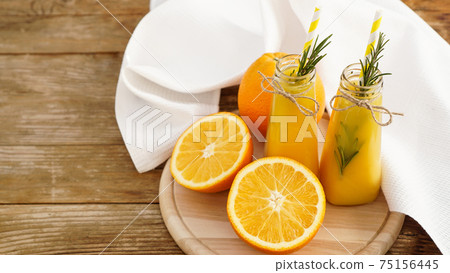 Orange juice in glass bottles. The juice is decorated with a sprig of rosemary Orange juice in glass bottles. The juice is decorated with a sprig of rosemary 75156445
