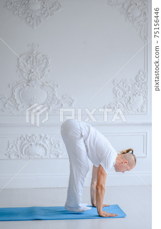 Man practicing advanced yoga against a white background Man practicing advanced yoga against a white background 75156446
