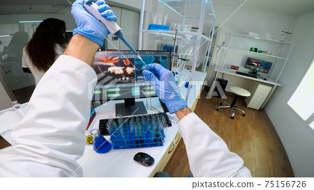 POV of scientist using micropipette in lab to extract blue liquide from test tubes 75156726