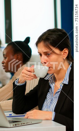 Concentrated manager typing on laptop sitting at desk in start up business Concentrated manager typing on laptop sitting at desk in start up business 75156734