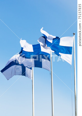 Three finnish national flags on the wind against the blue sky Three finnish national flags on the wind against the blue sky 75157835