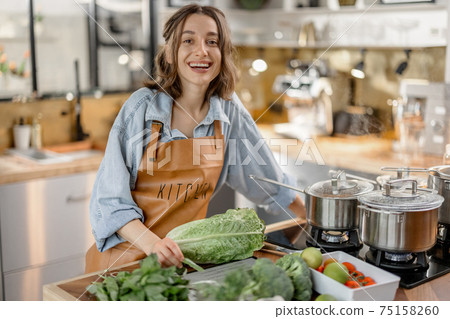 Woman with fresh green vegetables on the kitchen Woman with fresh green vegetables on the kitchen 75158260
