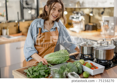 Woman with fresh green vegetables on the kitchen Woman with fresh green vegetables on the kitchen 75158270