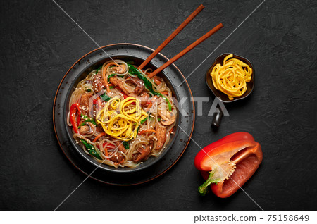 Japchae in black bowl on dark slate table top. Korean cuisine food glass chapchae noodles dish  75158649