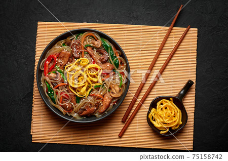 Japchae in black bowl on dark slate table top. Korean cuisine food glass chapchae noodles dish  75158742