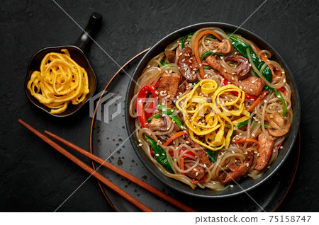Japchae in black bowl on dark slate table top. Korean cuisine food glass chapchae noodles dish Japchae in black bowl on dark slate table top. Korean cuisine food glass chapchae noodles dish 75158747