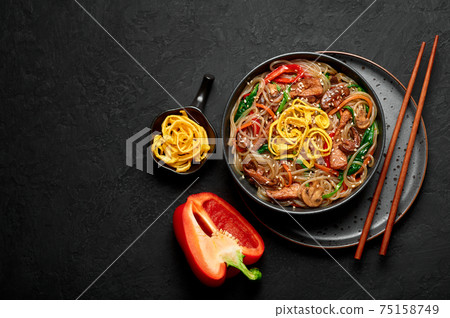 Japchae in black bowl on dark slate table top. Korean cuisine food glass chapchae noodles dish  75158749