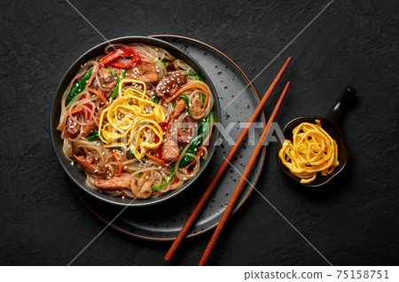 Japchae in black bowl on dark slate table top. Korean cuisine food glass chapchae noodles dish  75158751