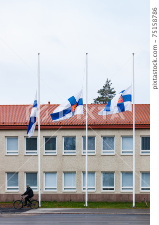 Three finnish flags lowered to half mast on the occasion of mourning at cloudy autumn day Three finnish flags lowered to half mast on the occasion of mourning at cloudy autumn day 75158786