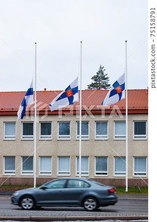 Three finnish flags lowered to half mast on the occasion of mourning at cloudy autumn day Three finnish flags lowered to half mast on the occasion of mourning at cloudy autumn day 75158791