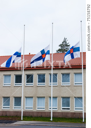Three finnish flags lowered to half mast on the occasion of mourning at cloudy autumn day Three finnish flags lowered to half mast on the occasion of mourning at cloudy autumn day 75158792