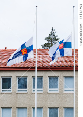 Two finnish flags lowered to half mast on the occasion of mourning at cloudy autumn day Two finnish flags lowered to half mast on the occasion of mourning at cloudy autumn day 75158793