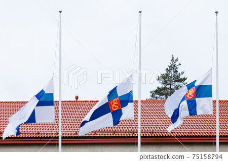 Three finnish flags lowered to half mast on the occasion of mourning at cloudy autumn day Three finnish flags lowered to half mast on the occasion of mourning at cloudy autumn day 75158794
