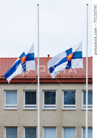 Three finnish flags lowered to half mast on the occasion of mourning at cloudy autumn day Three finnish flags lowered to half mast on the occasion of mourning at cloudy autumn day 75158795