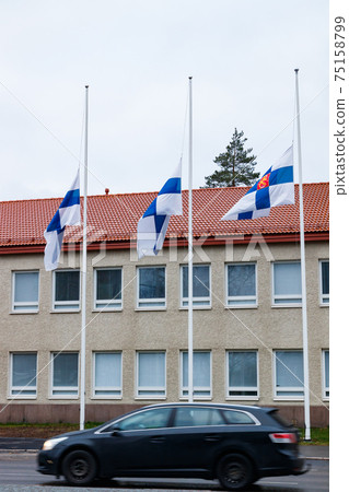 Three finnish flags lowered to half mast on the occasion of mourning at cloudy autumn day 75158799