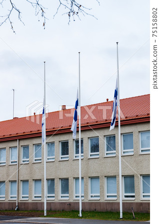 Three finnish flags lowered to half mast on the occasion of mourning at cloudy autumn day Three finnish flags lowered to half mast on the occasion of mourning at cloudy autumn day 75158802