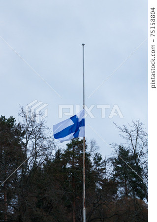 Finnish flag lowered to half mast on the occasion of mourning at cloudy autumn day Finnish flag lowered to half mast on the occasion of mourning at cloudy autumn day 75158804