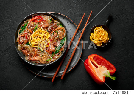 Japchae in black bowl on dark slate table top. Korean cuisine food glass chapchae noodles dish Japchae in black bowl on dark slate table top. Korean cuisine food glass chapchae noodles dish 75158811