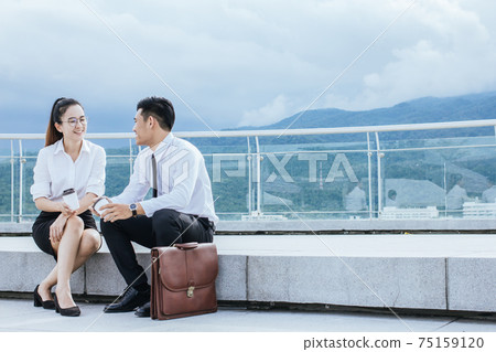 Asian.Businessman and woman holding hot coffee are smiling.Relax , Meetings the commercial processes involved in promoting. Asian.Businessman and woman holding hot coffee are smiling.Relax , Meetings the commercial processes involved in promoting. 75159120