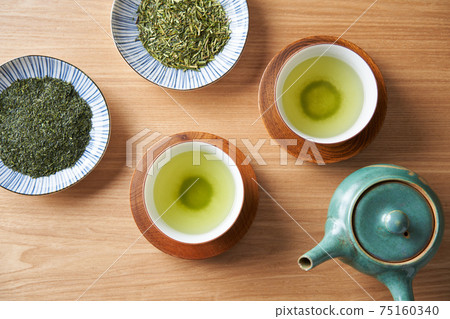 Green tea and tea leaves poured into a teacup 75160340