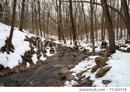 A man and a woman rest on a bench by a winter forest stream A man and a woman rest on a bench by a winter forest stream 75160556