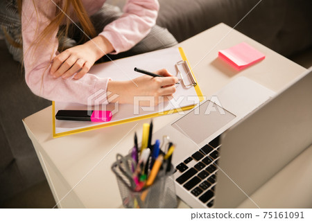 Close up hands of girl writing during group video call, use video conference with teacher, listening to online course 75161091