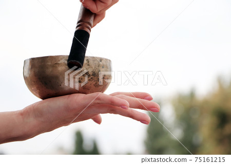 Musical instrument - singing Himalayan bowl. The singing bell holds the girl in his hand. The practice of healing vibrations, surya, yoga, meditation 75161215