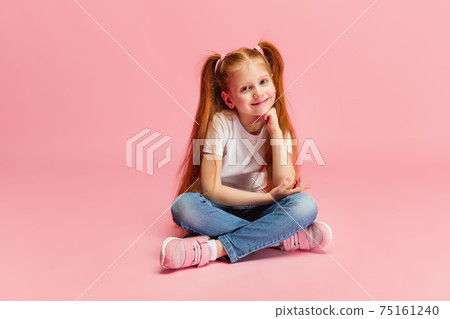 Happy caucasian little girl isolated on pink studio background. Looks happy, cheerful, sincere. Copyspace. Childhood, education, emotions concept 75161240