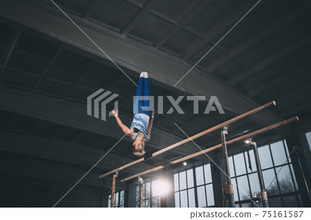 Little male gymnast training in gym, flexible and active. Caucasian fit little boy, athlete in sportswear practicing in exercises for strength, balance. Little male gymnast training in gym, flexible and active. Caucasian fit little boy, athlete in sportswear practicing in exercises for strength, balance. 75161587