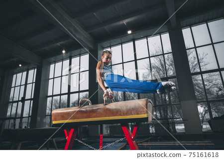 Little male gymnast training in gym, flexible and active. Caucasian fit little boy, athlete in sportswear practicing in exercises for strength, balance. 75161618