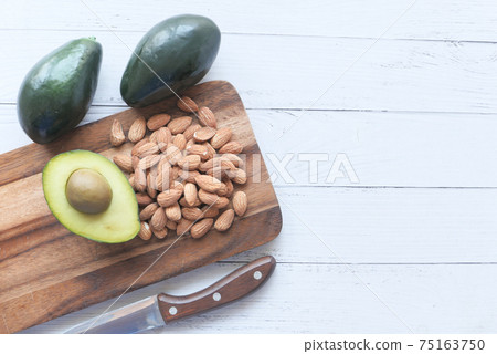 top view of slice of avocado and nut on chopping board with copy space  75163750