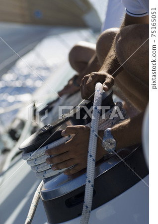 Sailor tying rope onto windlass close-up of hands 75165051