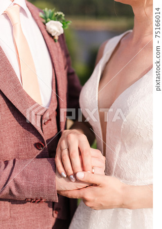 the groom and the bride hold hands. White wedding dress 75166014