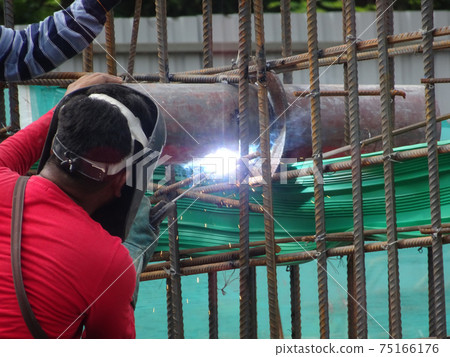 SELANGOR, MALAYSIA -MAY 16, 2017: Welder wearing protective mask during welding metal at the construction site. SELANGOR, MALAYSIA -MAY 16, 2017: Welder wearing protective mask during welding metal at the construction site. 75166176