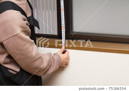 Woman measuring curtain dimensions 75166354