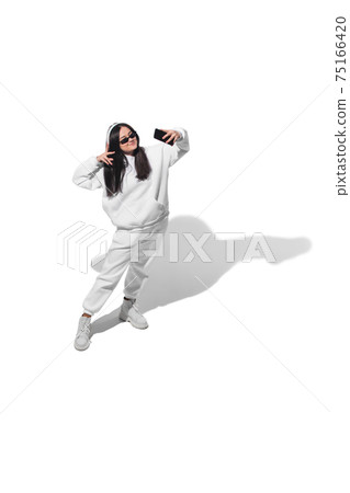 High angle view of young woman on white studio background. Girl in motion or movement. Human emotions and facial expressions concept High angle view of young woman on white studio background. Girl in motion or movement. Human emotions and facial expressions concept 75166420