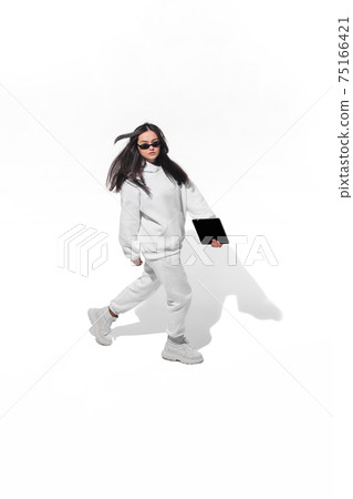 High angle view of young woman on white studio background. Girl in motion or movement. Human emotions and facial expressions concept High angle view of young woman on white studio background. Girl in motion or movement. Human emotions and facial expressions concept 75166421