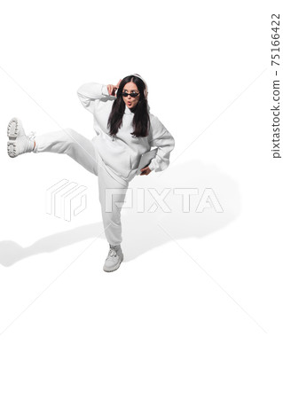 High angle view of young woman on white studio background. Girl in motion or movement. Human emotions and facial expressions concept High angle view of young woman on white studio background. Girl in motion or movement. Human emotions and facial expressions concept 75166422