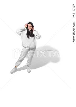 High angle view of young woman on white studio background. Girl in motion or movement. Human emotions and facial expressions concept High angle view of young woman on white studio background. Girl in motion or movement. Human emotions and facial expressions concept 75166424