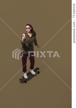 High angle view of young woman on brown studio background. Girl in motion or movement. Human emotions and facial expressions concept High angle view of young woman on brown studio background. Girl in motion or movement. Human emotions and facial expressions concept 75166438