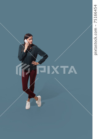 High angle view of young woman on blue studio background. Girl in motion or movement. Human emotions and facial expressions concept 75166454