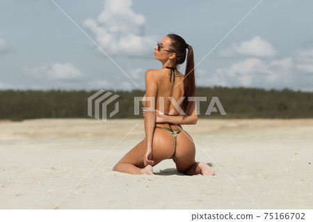 Seductive lady doing hair on beach Seductive lady doing hair on beach 75166702