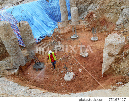 KUALA LUMPUR, MALAYSIA -JULY 30, 2020: Construction workers mixing and spraying the anti-termite chemical treatment to the soil at the construction site. KUALA LUMPUR, MALAYSIA -JULY 30, 2020: Construction workers mixing and spraying the anti-termite chemical treatment to the soil at the construction site. 75167427