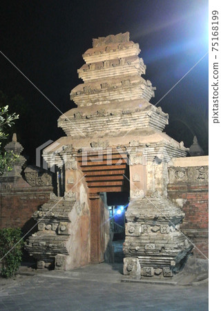 JOGJAKARTA, INDONESIA -JUNE 12, 2014: Entrance arch at old Masjid Besar Mataram Kotagede, Jogjakarta Indonesia. The arch was made from brick and hand made carving stone in traditional Balinese Style JOGJAKARTA, INDONESIA -JUNE 12, 2014: Entrance arch at old Masjid Besar Mataram Kotagede, Jogjakarta Indonesia. The arch was made from brick and hand made carving stone in traditional Balinese Style 75168199