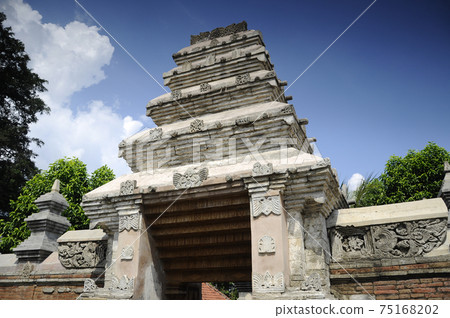 JOGJAKARTA, INDONESIA -JUNE 12, 2014: Entrance arch at old Masjid Besar Mataram Kotagede, Jogjakarta Indonesia. The arch was made from brick and hand made carving stone in traditional Balinese Style JOGJAKARTA, INDONESIA -JUNE 12, 2014: Entrance arch at old Masjid Besar Mataram Kotagede, Jogjakarta Indonesia. The arch was made from brick and hand made carving stone in traditional Balinese Style 75168202