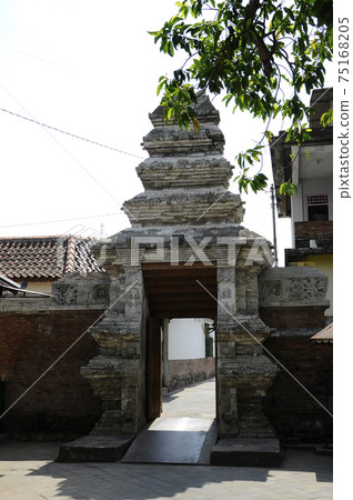 JOGJAKARTA, INDONESIA -JUNE 12, 2014: Entrance arch at old Masjid Besar Mataram Kotagede, Jogjakarta Indonesia. The arch was made from brick and hand made carving stone in traditional Balinese Style JOGJAKARTA, INDONESIA -JUNE 12, 2014: Entrance arch at old Masjid Besar Mataram Kotagede, Jogjakarta Indonesia. The arch was made from brick and hand made carving stone in traditional Balinese Style 75168205
